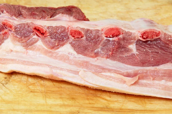 Costillas de cerdo crudas apetitosas en tabla de cortar de madera . — Foto de Stock