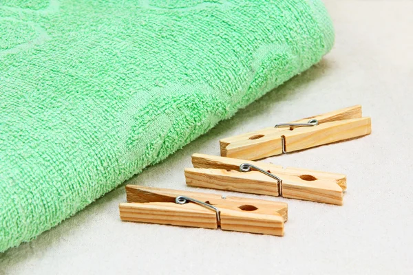 Green towel and wooden clothespins on white fabric. — Stock Photo, Image