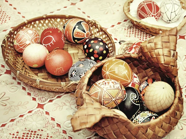 Multicolored easter eggs in straw pots on a table.Toned image. — Stock Photo, Image