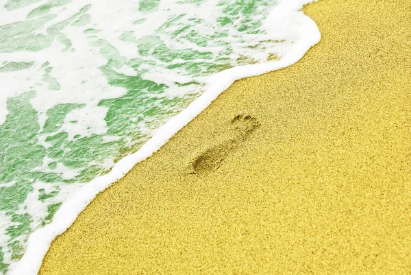 Ανθρώπινη ίχνος στην αμμώδη παραλία κοντά surf γαλάζια θάλασσα. — Φωτογραφία Αρχείου