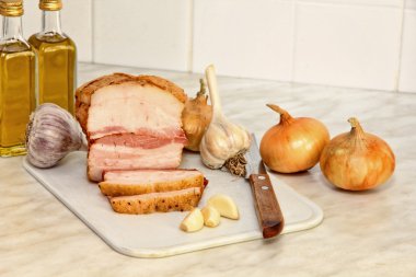 Mutfak masasının üstünde dilimlenmiş domuz eti ve sebze.