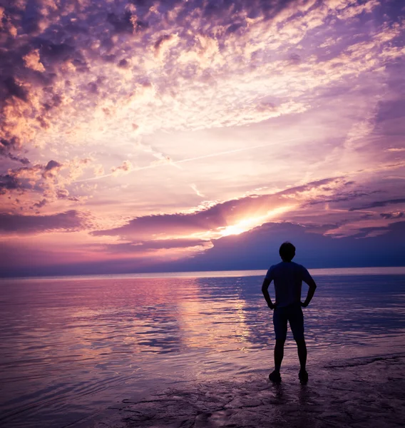 Silueta del hombre disfrutando de la puesta de sol en el mar Imágenes De Stock Sin Royalties Gratis