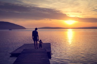 Bir baba ile oğlu deniz kenarında siluetleri