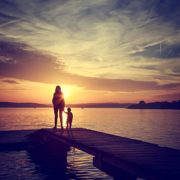 Silhouetten van moeder met haar zoon door de zee — Stockfoto