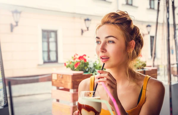 Jovem mulher bebendo café gelado em um café — Fotografia de Stock