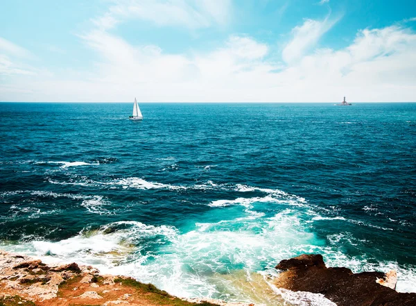 Deniz feneri ile deniz manzarası tonda ve yelkenli yat — Stok fotoğraf
