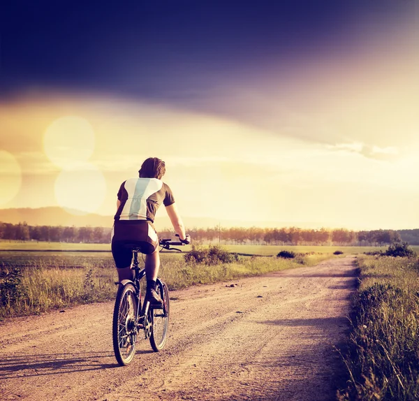 Ciclista a andar de bicicleta na Country Road. Foto tonificada — Fotografia de Stock