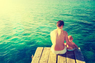 Küçük bebeği rahatlatıcı deniz kenarında babasıyla