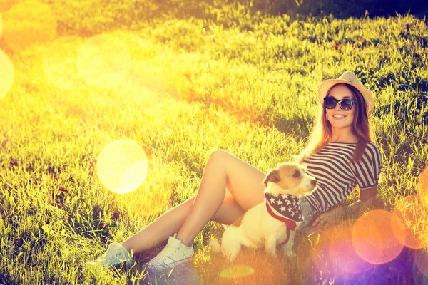 Hipster meisje met haar hond liggend op het gras — Stockfoto