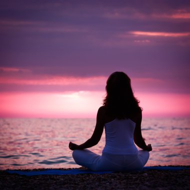 Denizin kenarında Lotus pozisyonda meditasyon kadın