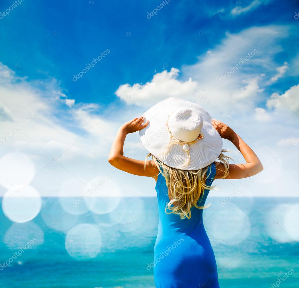 Woman in Blue Dress and Hat at Sea. Back View.