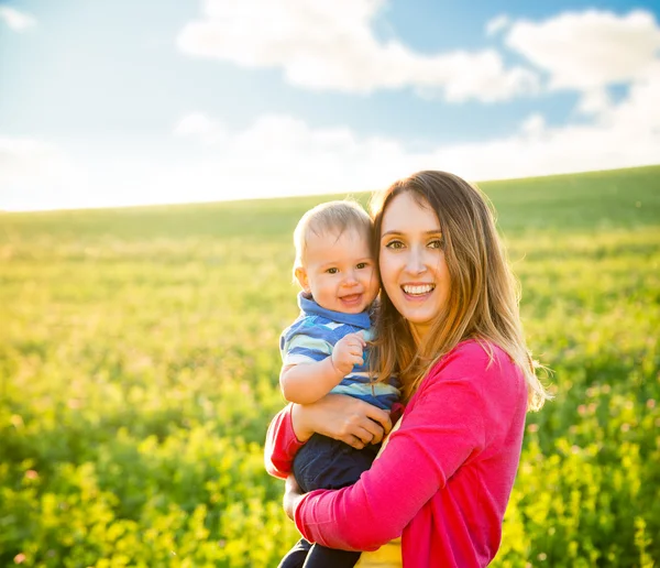 Jonge gelukkig moeder met haar glimlachende Baby buiten — Stockfoto