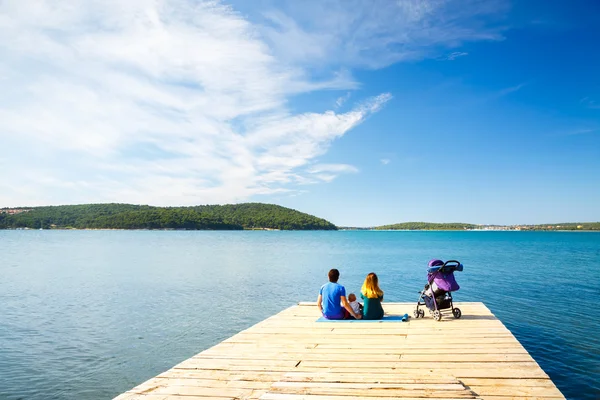 Familj med lilla Baby sitter på Pier nära havet — Stockfoto