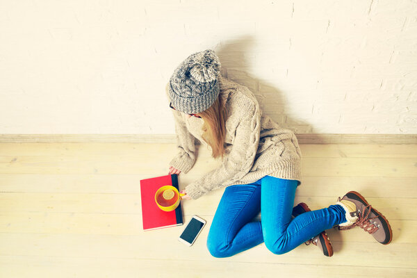 Young Woman Sitting on the Wooden Floor with a Tea