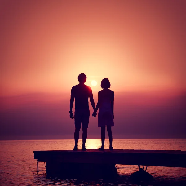 Pareja romántica disfrutando de la puesta de sol en el mar . — Foto de Stock