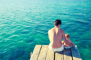 Genç Baba denizin kenarında rahatlatıcı oğluyla