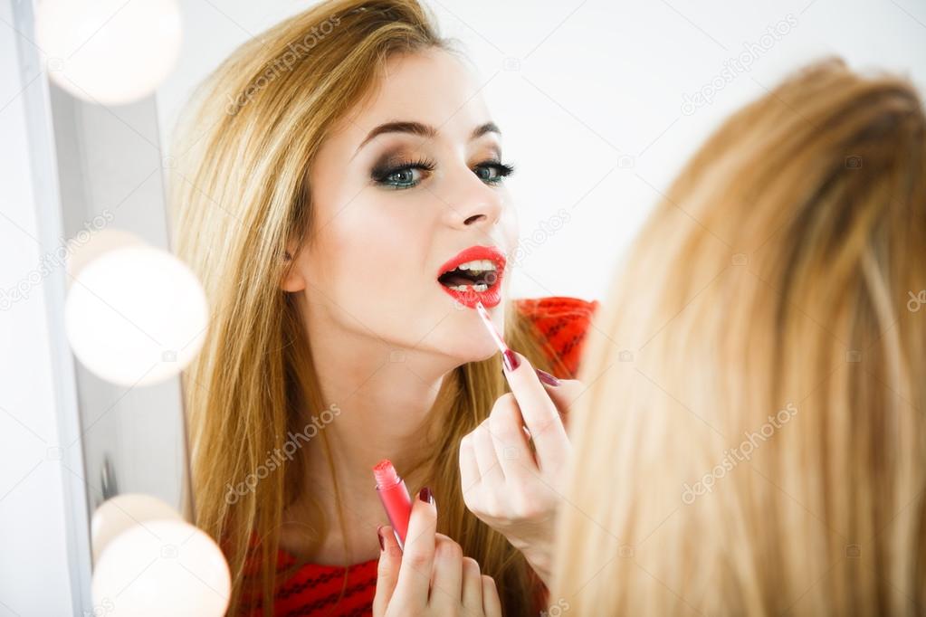 Beautiful Woman Applying Lipstick at the Mirror