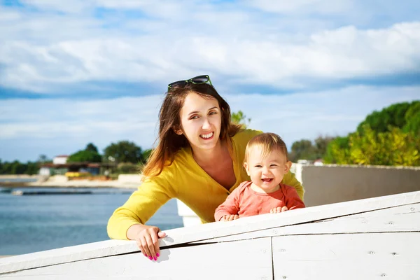 Mutlu küçük bebek ve anne denizin kenarında gülümseyen — Stok fotoğraf