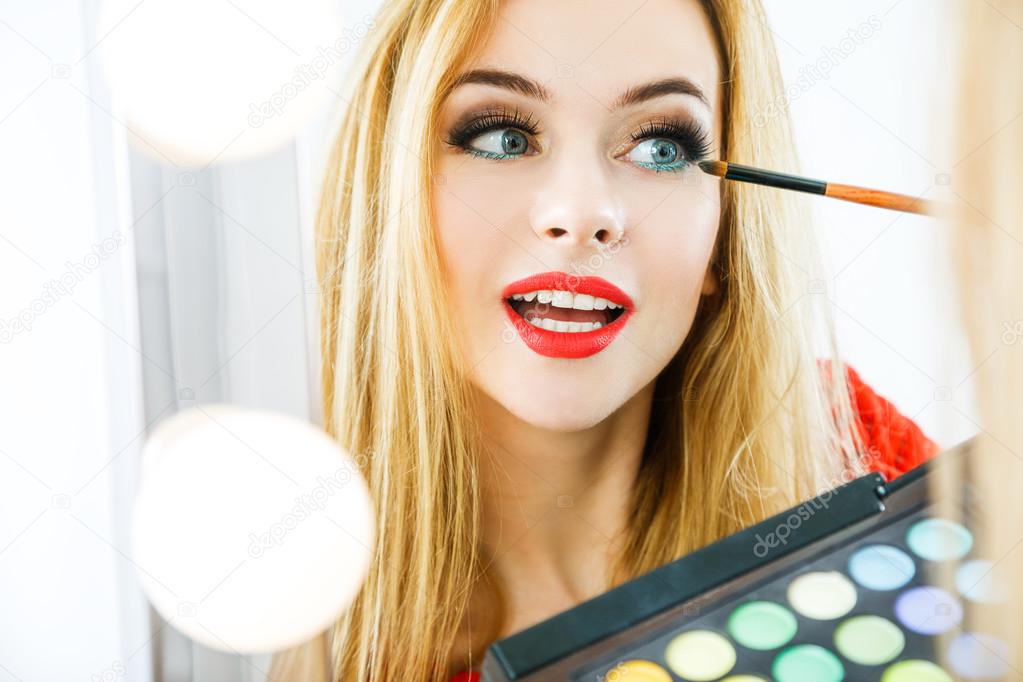 Beautiful Woman Applying Makeup at the Mirror