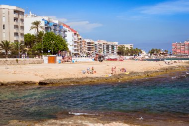 Torrevieja, İspanya - 13 Eylül 2014: Güneşli Akdeniz beach, sıcak kum altında şemsiye şezlong üzerinde turist dinlenin. İnsanlar deniz, kristal berraklığında tuzlu suda yıkanmak Torrevieja, İspanya topluluk Cala del Palangre, İspanya