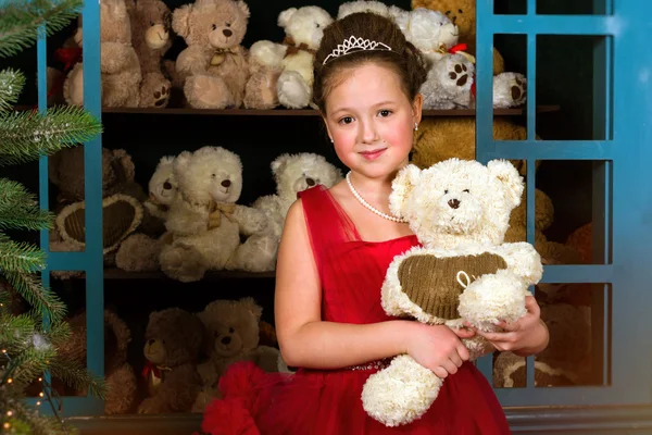 Menina em um vestido vermelho abraçando um ursinho de pelúcia — Fotografia de Stock