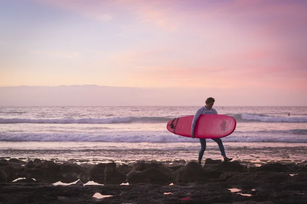 Surfers surf on the waves, bright sunset on the coast, Tenerife,