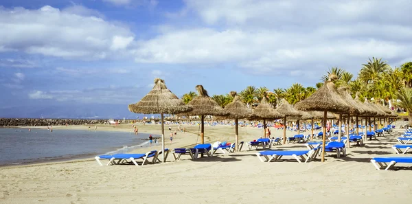 Szalma napernyő és nyugágy a Playa de Las Americas, Tener — Stock Fotó