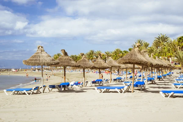 Slaměné slunečníky a lehátka na Playa de Las Americas, Tener — Stock fotografie