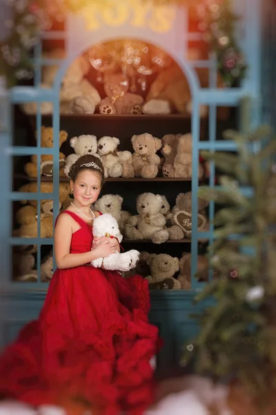 Menina em um vestido vermelho abraçando um ursinho de pelúcia — Fotografia de Stock