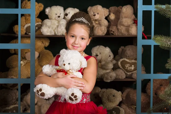 Menina em um vestido vermelho abraçando um ursinho de pelúcia — Fotografia de Stock