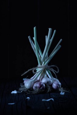 Basit bir sarımsak ipiyle bağlanmış bir demet taze sarımsak soğanı içeren dramatik ve sanatsal bir hayat. Kompozisyon, radardaki doğal dokuları ve derin gölgeleri vurgulayan karamsar, serin tonlu ay ışığıyla aydınlanıyor.