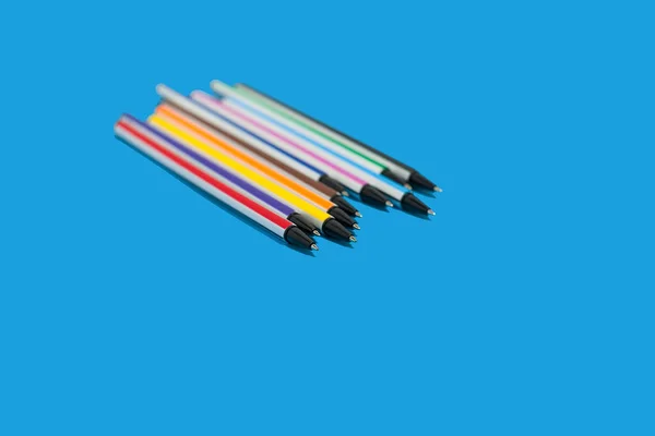 Кольорові ручки лежать на синьому фоні — стокове фото