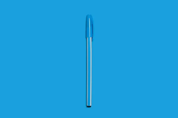 Светло-голубая пластиковая ручка на темно-голубом фоне. офисные принадлежности — стоковое фото