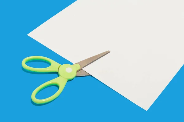 Plastic scissors cutting a paper. school accessories — Stock Photo, Image