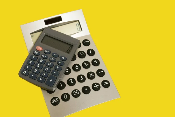 Dwa kalkulatory na żółtej powierzchni. akcesoria biurowe. szkoła — Zdjęcie stockowe