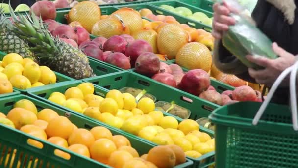 買い手は店内の果物や野菜を選択します 女性はキュウリとオレンジを買う 使い捨てのビニール袋に野菜を入れて — ストック動画