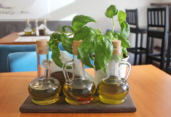 Albahaca fresca y aceite de oliva en una jarra sobre la mesa — Foto de Stock