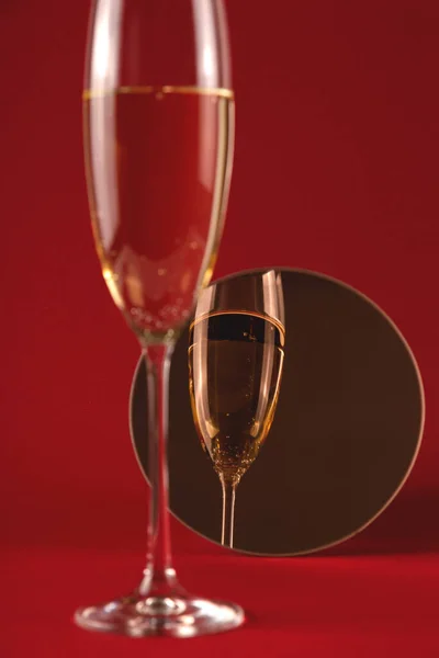 Copo elegante de champanhe em um posto em um fundo vermelho — Fotografia de Stock