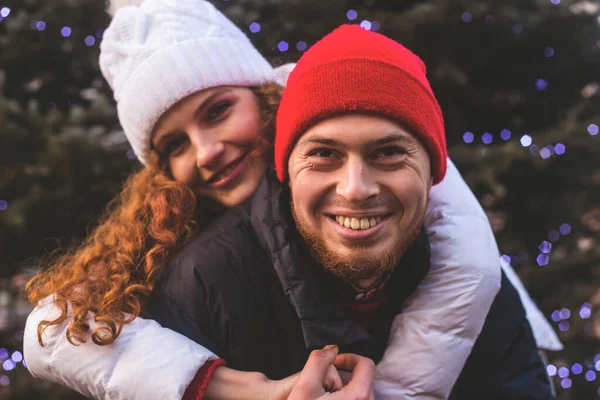 Loving boyfriend and girlfriend are hugging by Christmas tree — Stock Photo, Image