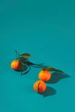 Turkuaz arka planda gölgeli mandalinalar