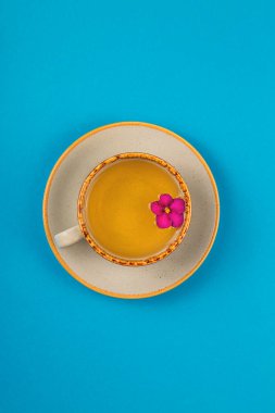 Parlak mavi arkaplanda çiçekler olan bir fincan çay.