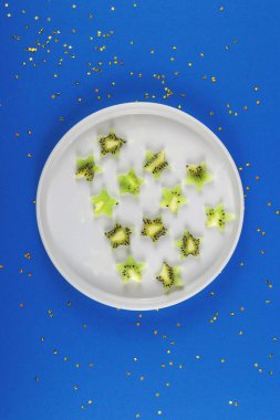 Kivi, mavi arka planda sağlıklı bir uykuyu geri getirmek için bir tabakta yıldız şeklinde dilimler..