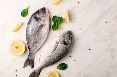 Dorado balığı, limon ve yeşil yapraklar mermer masada su damlaları ve karabiberli