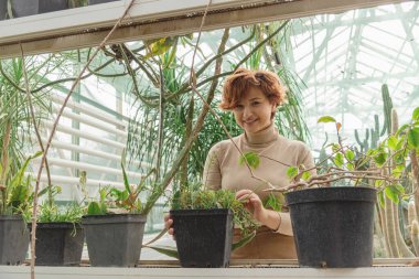 Güzel ve iri bir kadın bitkilerle ilgilenir. 