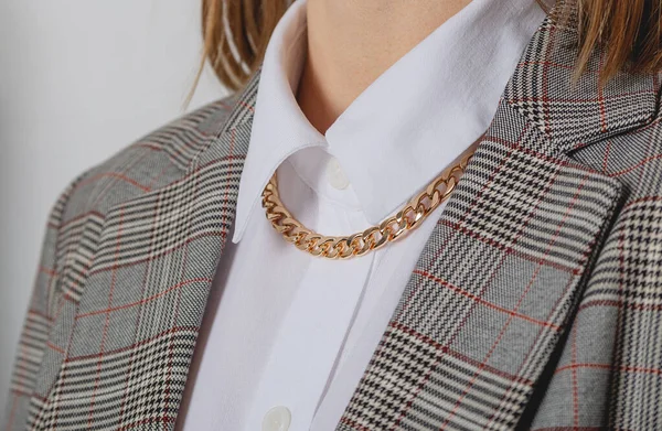 Gold chain accessory with white shirt and jacket in business woman style.