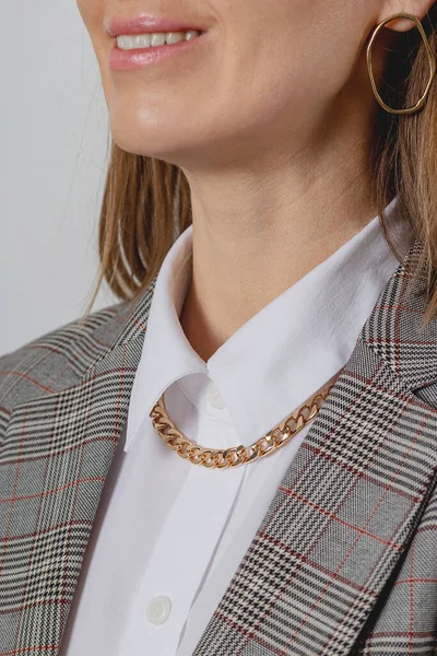 Gold chain accessory with white shirt and jacket in business woman style.