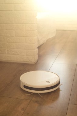 İçerideki akıllı robot süpürgesi lamine zemini temizliyor.