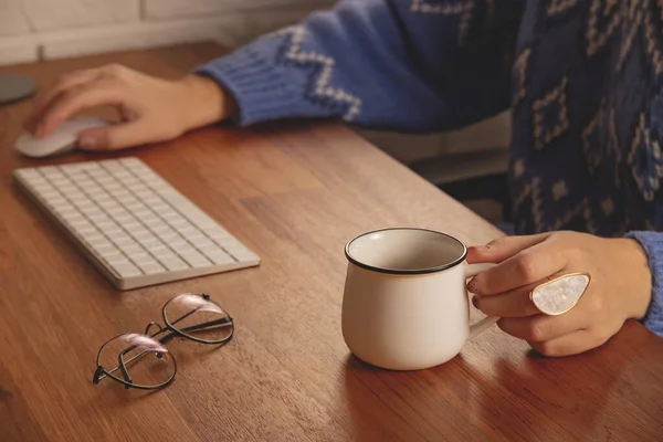 The woman works from home at the computer. Workplace at a wooden table in a cozy home