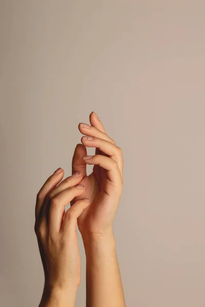 Les mains des femmes se lèvent. Avec manucure minimaliste sur fond sombre — Photo