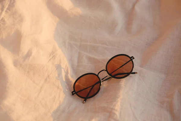 Gafas de sol sobre un paño blanco en la playa a la luz del sol. —  Fotos de Stock